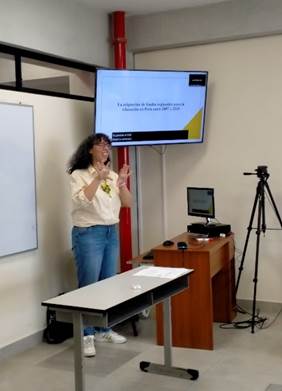 A person standing in front of a screen

Description automatically generated